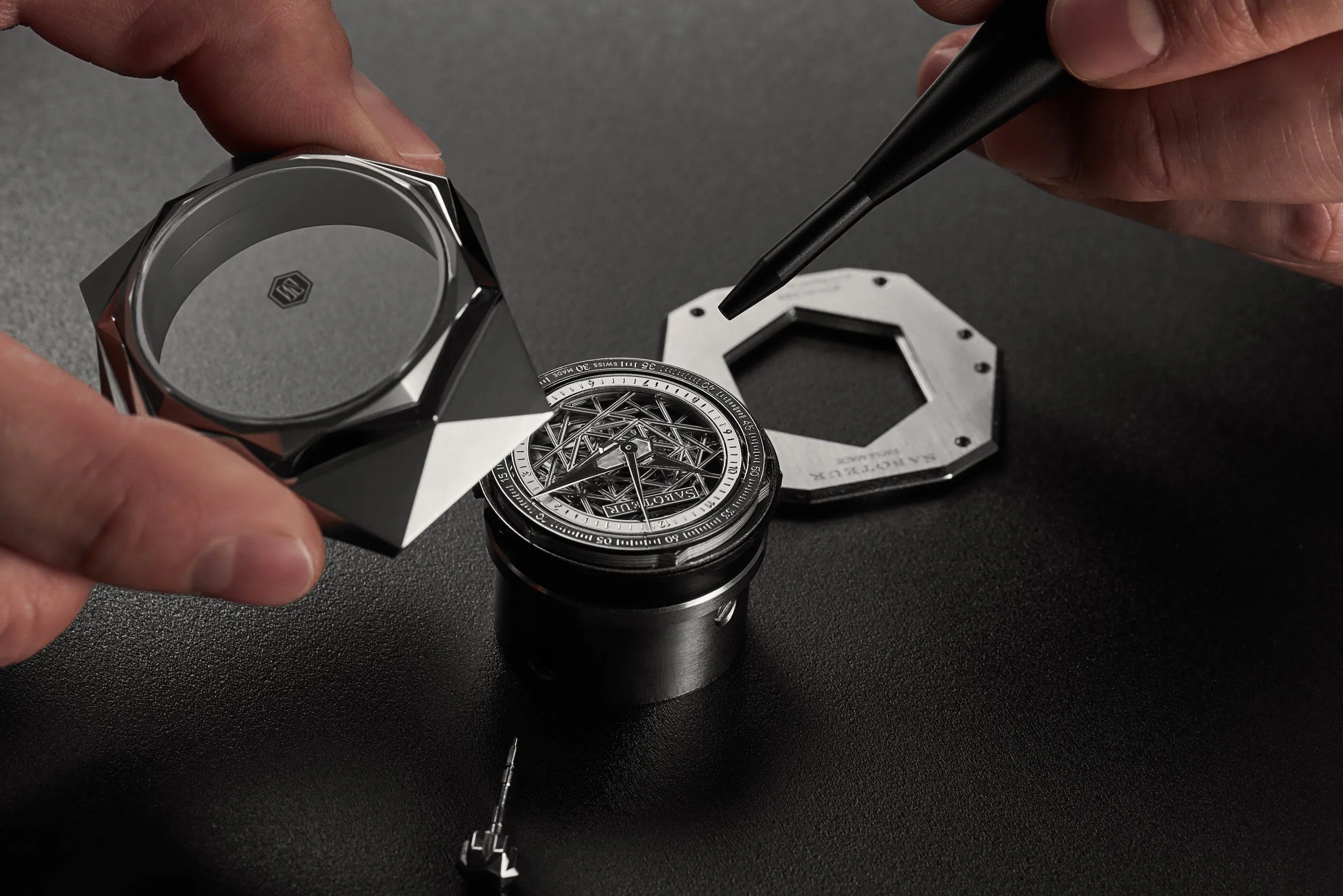 Hands assembling a faceted watch case and its skeleton movement, ACTE.5